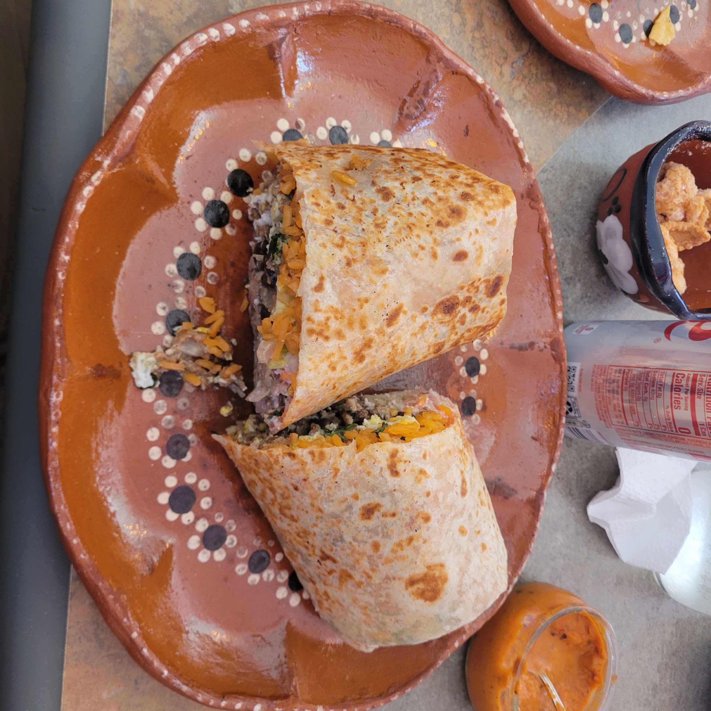 A griddled burrito sliced in half on a decorated clay plate